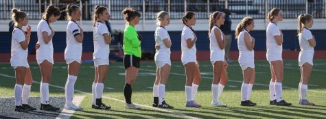 The girls varsity soccer team stands for the national anthem, as they prepare for the game. 