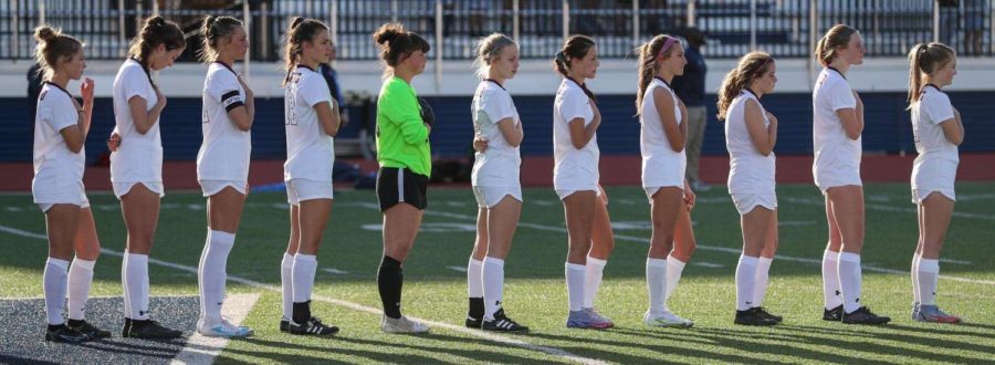 The+girls+varsity+soccer+team+stands+for+the+national+anthem%2C+as+they+prepare+for+the+game.+