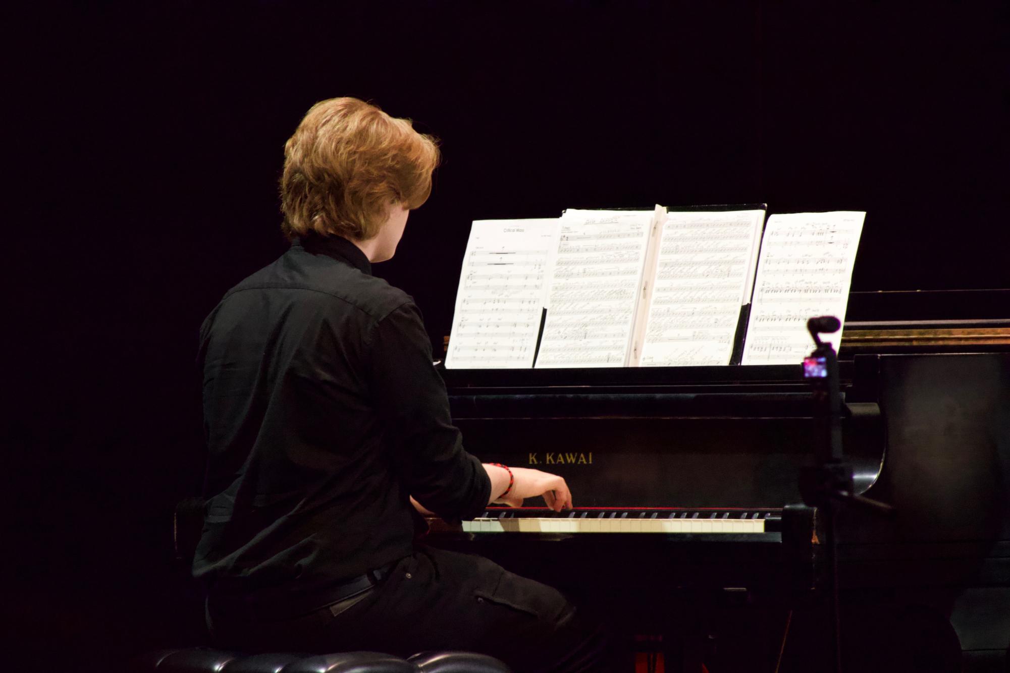 The audience finds its seats in the auditorium, anxiously awaiting the start of the concert. On stage, a group of musicians takes their places.