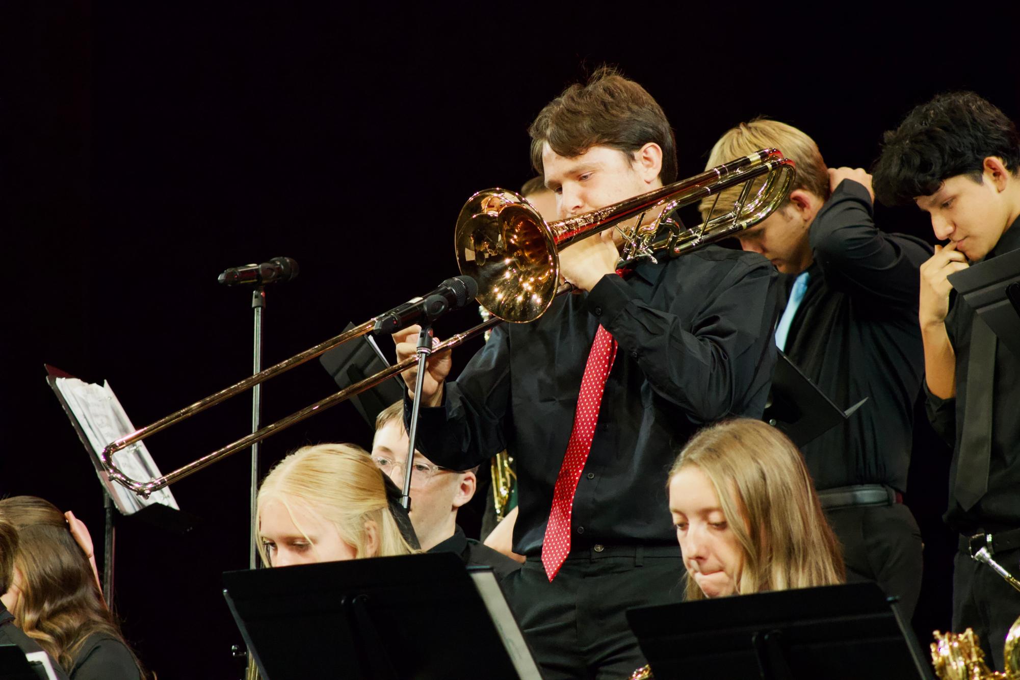 The audience finds its seats in the auditorium, anxiously awaiting the start of the concert. On stage, a group of musicians takes their places.
