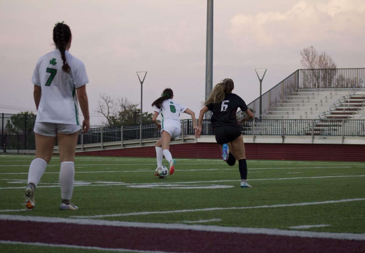 A Bishop McGuinness team member waits for a pass from s teammate, and Mia Madden runs to intercept the ball.
