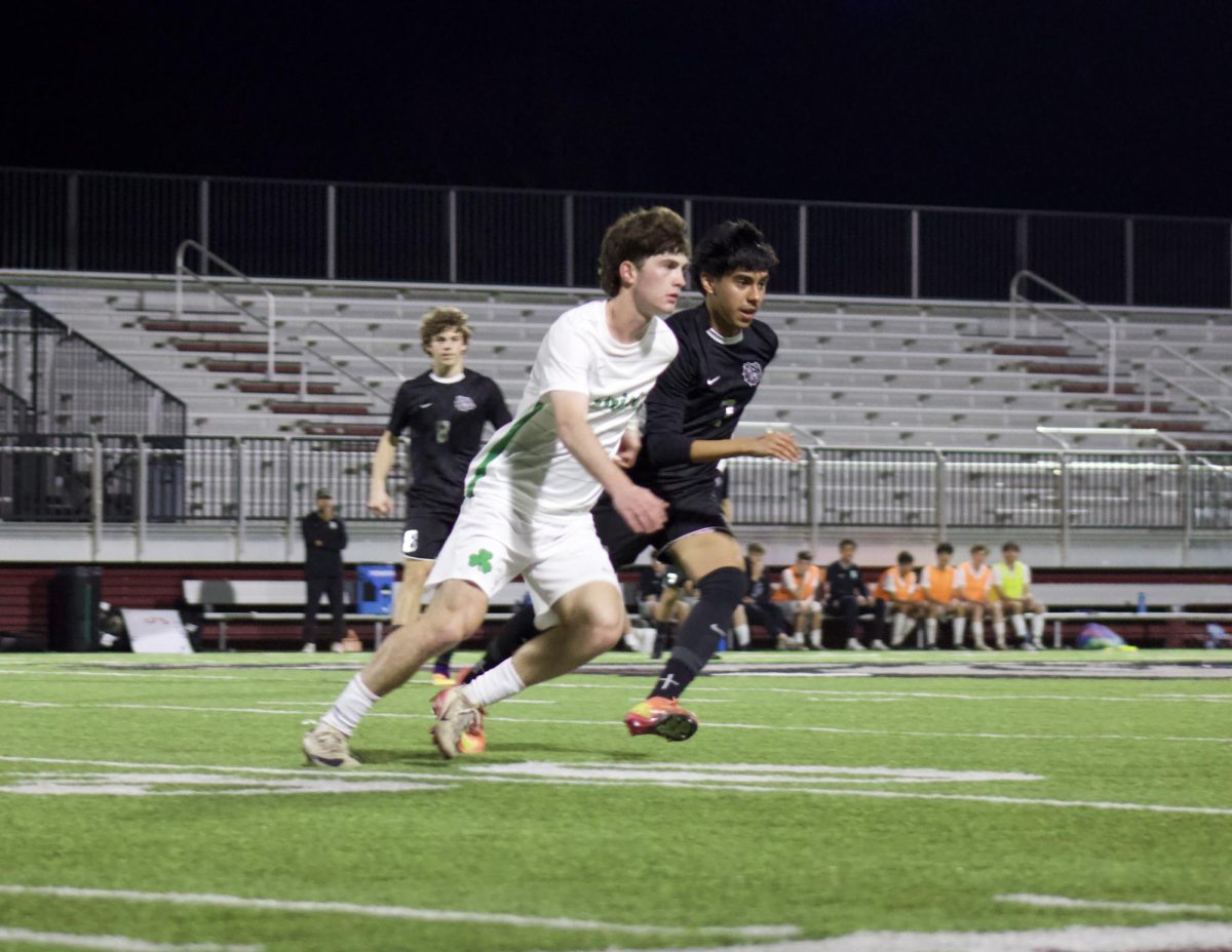 A player from Bishop McGuinness and Yahir Chavez chase after the ball in full speed in hopes of winning.