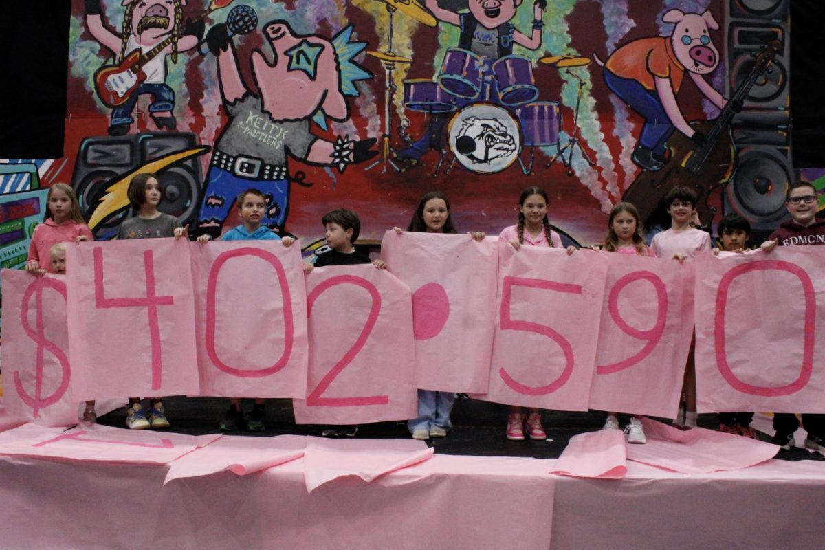 The students from Memorial's feeder elementary schools show the audience the total money raised for Special Care, which is $402,590.