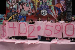The students from Memorial's feeder elementary schools show the audience the total money raised for Special Care, which is $402,590.