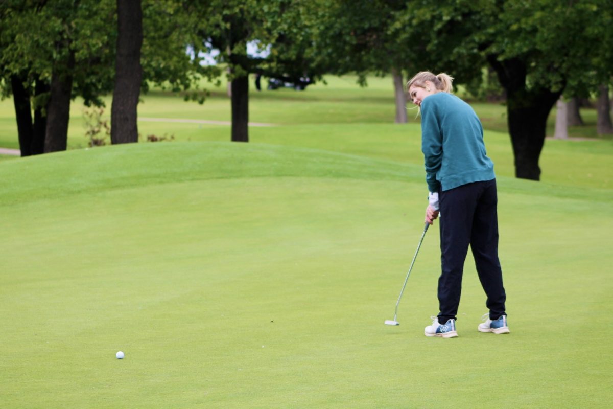 Sophomore Reagan Highsmith smiles as she softly putts the ball down hill.